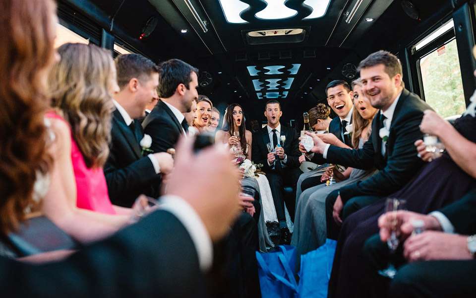 Wedding party toasting with champagne inside a party bus with LED ceiling lights
