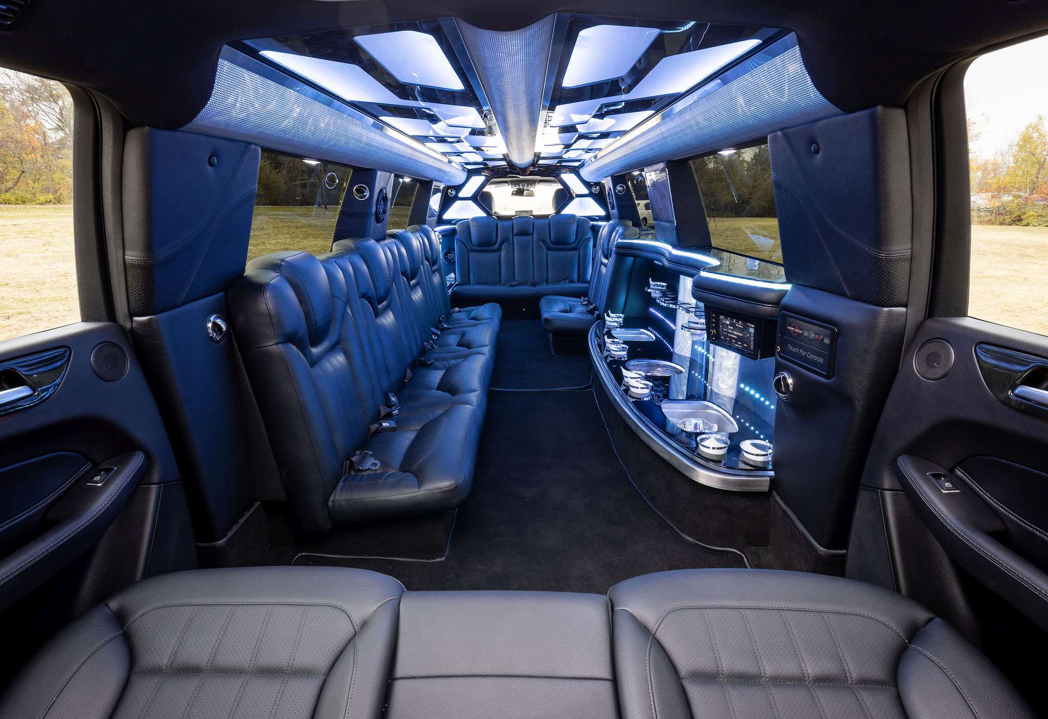 Stretch SUV limousine interior with black leather side seats, lit ceiling and bar