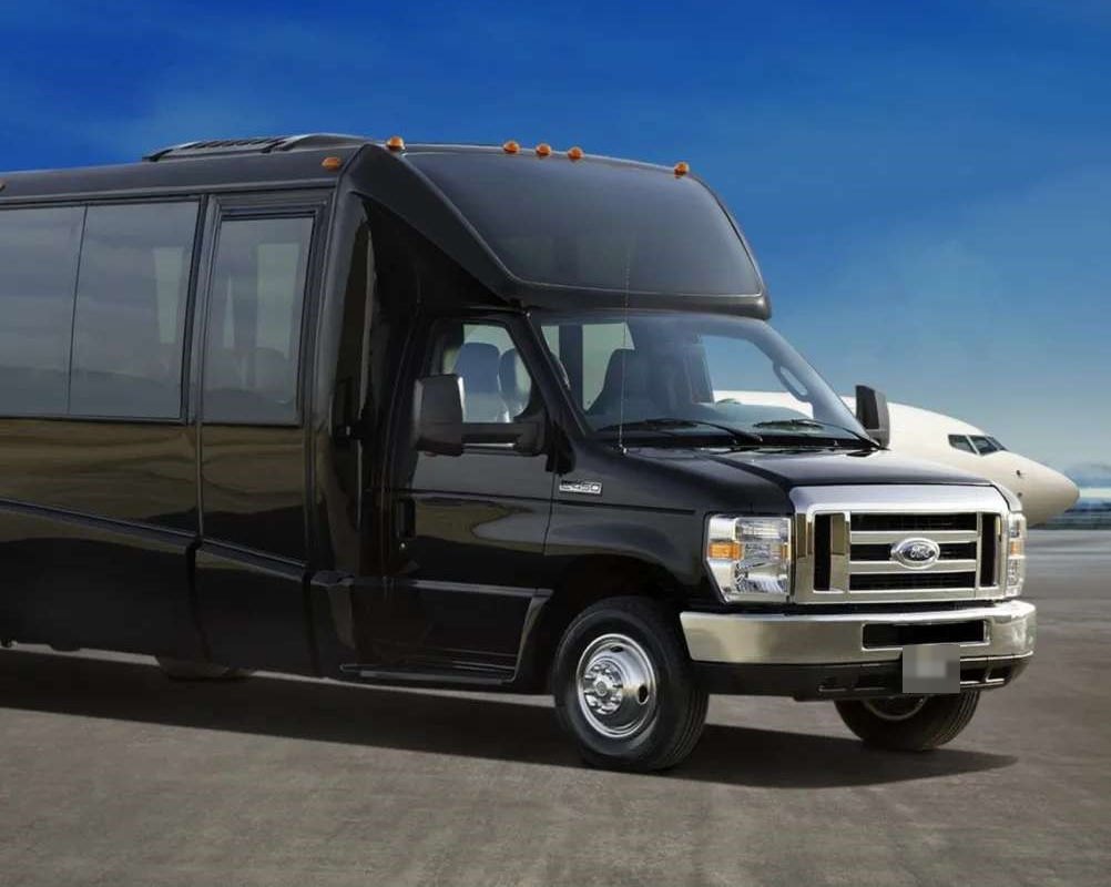 Black Ford limo bus on an airfield with a private jet behind