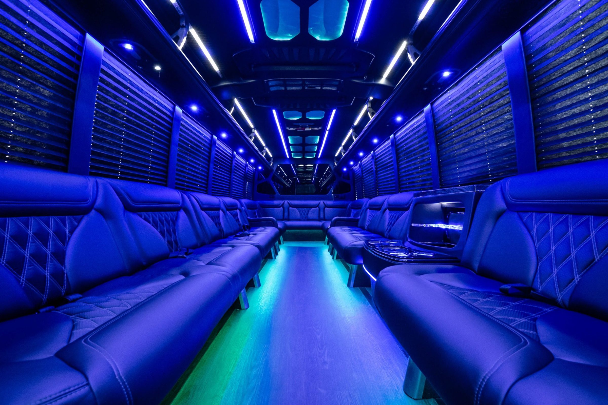 Party bus interior with blue LED lighting, quilted leather side seating and a lit floor