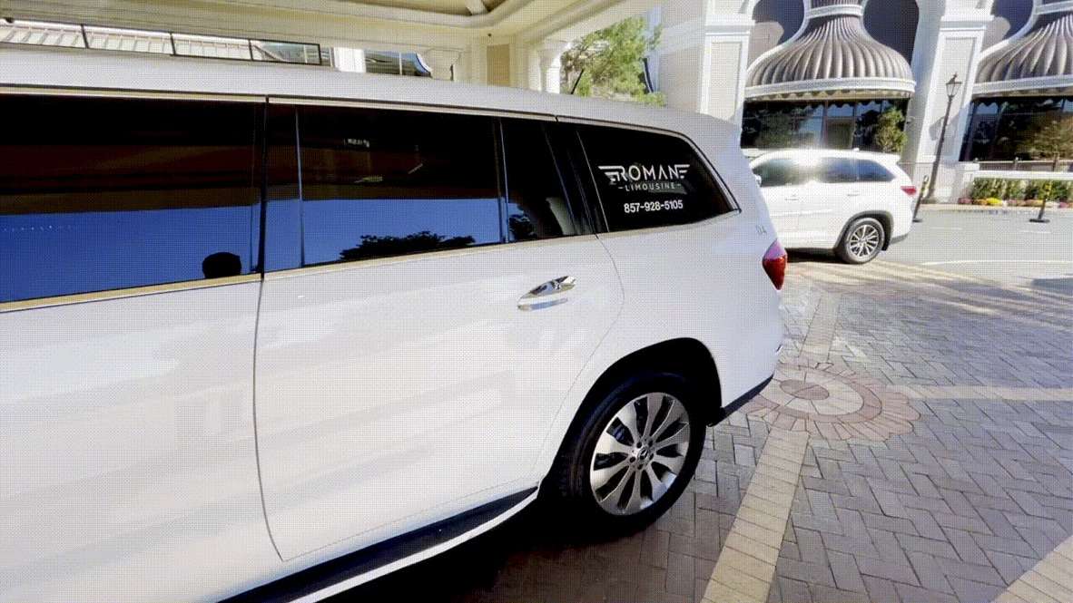 White SUV with Roman Limousine lettering parked at a covered building entrance