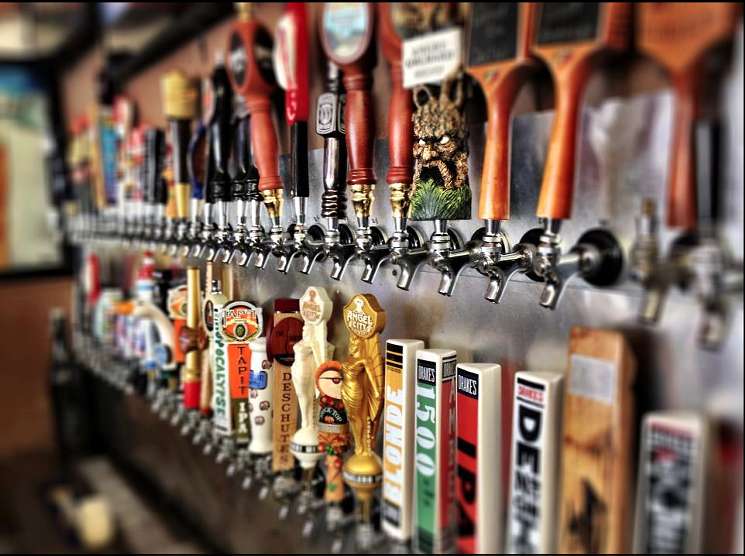 Row of beer taps with colorful craft beer handles at a bar