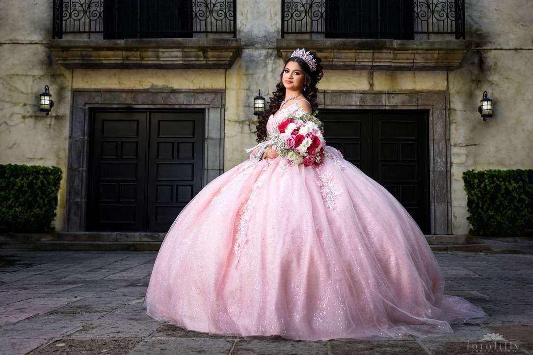 Girl in a pink quinceañera ball gown and tiara holding a bouquet of roses