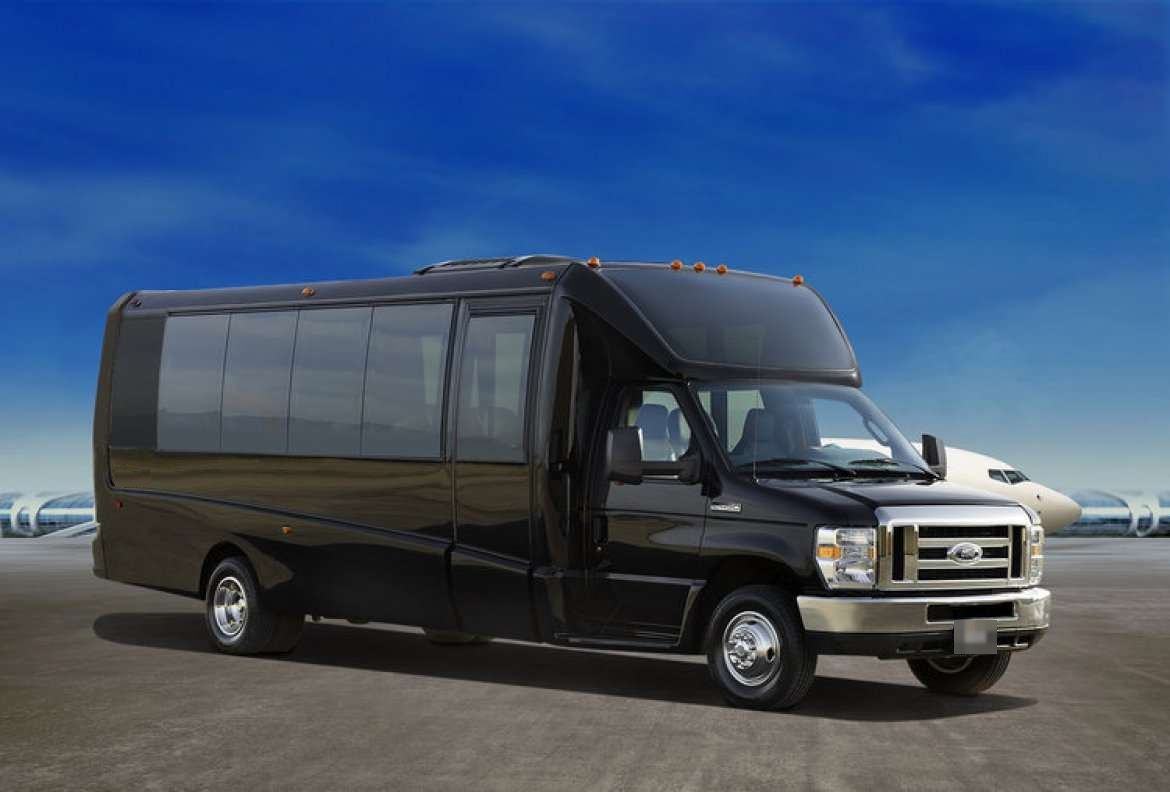 Black Ford limo bus parked on an airfield with a private jet behind