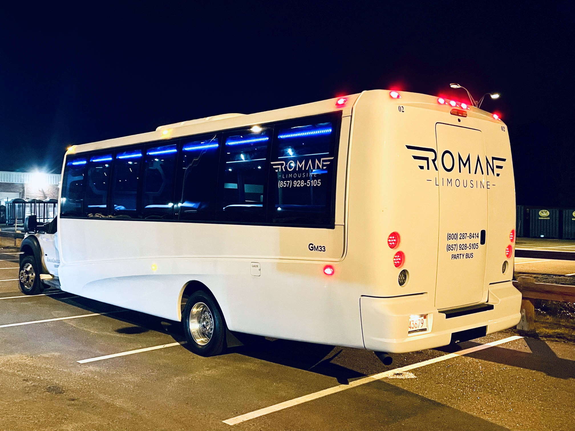 White Roman Limousine party bus at night, rear view, blue lights in the windows