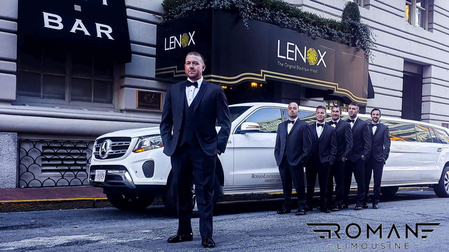 Groom and groomsmen in tuxedos by a white Mercedes-Benz stretch limo outside the Lenox hotel