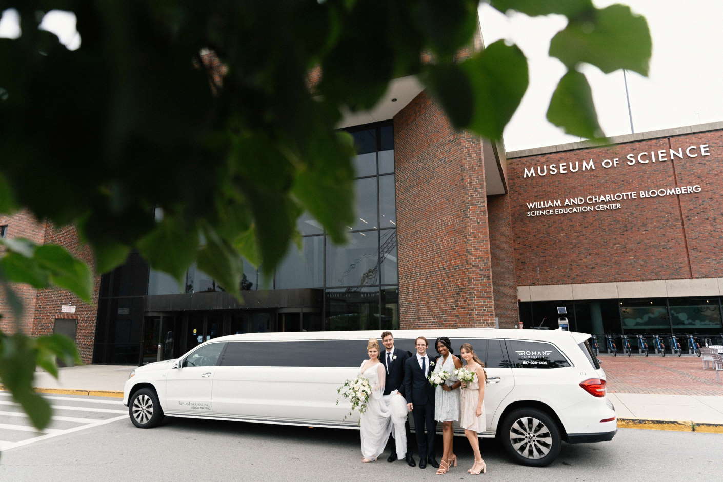 Bride and groom with friends beside a white stretch SUV limo, Museum of Science behind