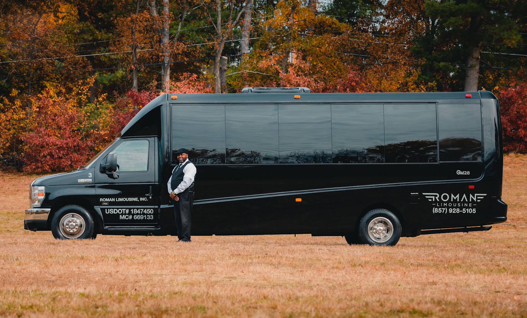 Chauffeur standing beside a black limo bus with Roman Limousine lettering
