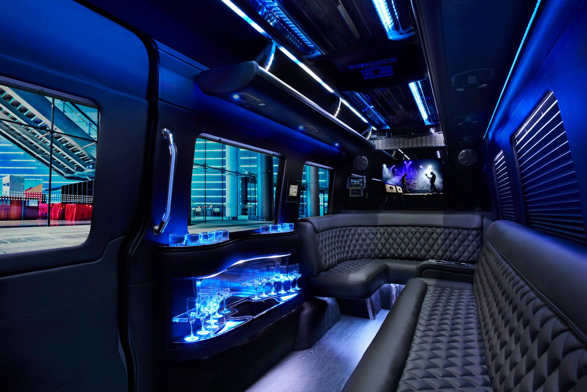 Limo van interior with black quilted leather seats, lit bar, blue LED ceiling and TV