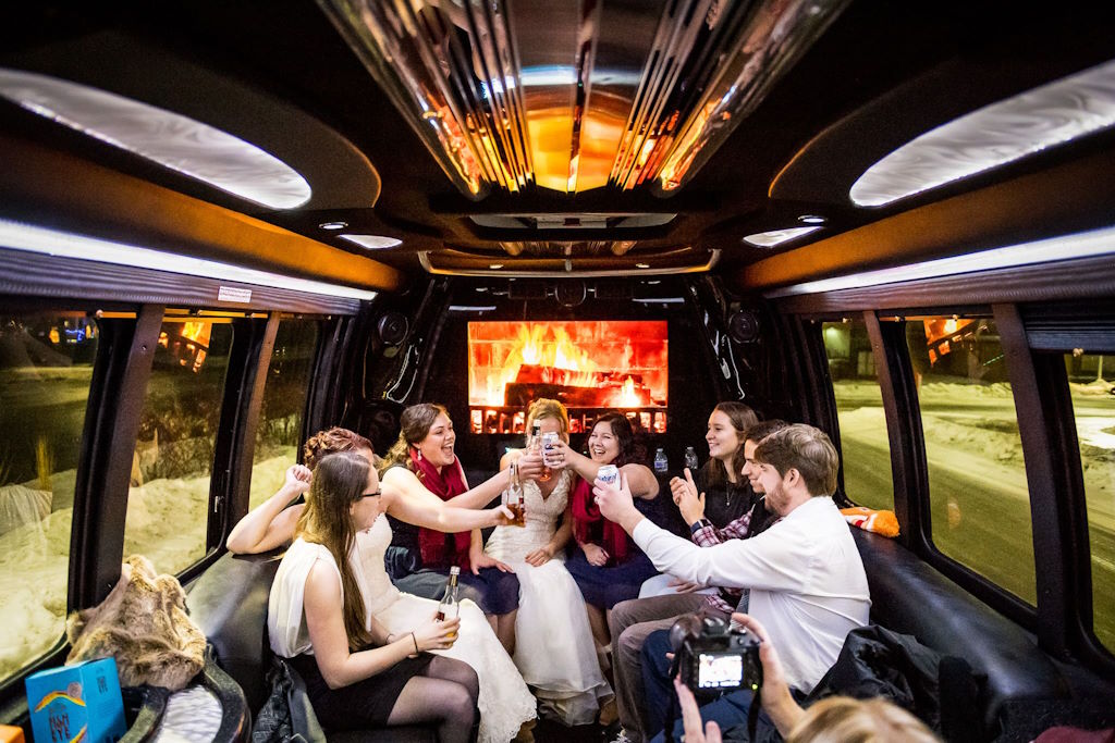 Bride and friends toasting inside a party bus, snow visible through the windows