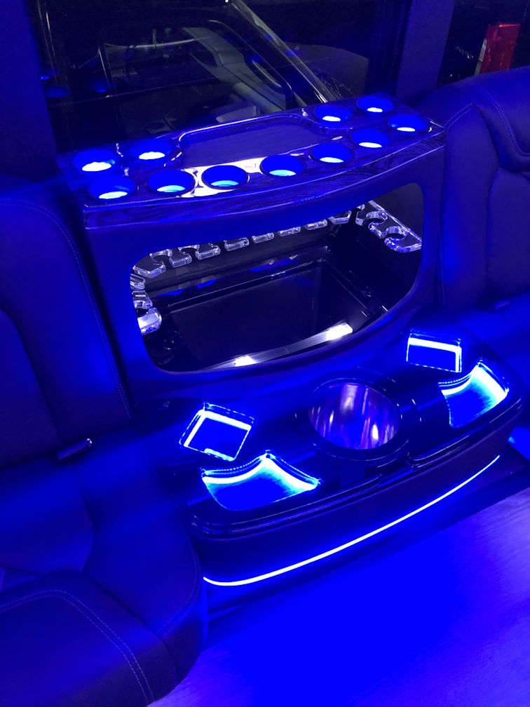 Bar console with blue LED cup holders and a glass rack inside a limousine