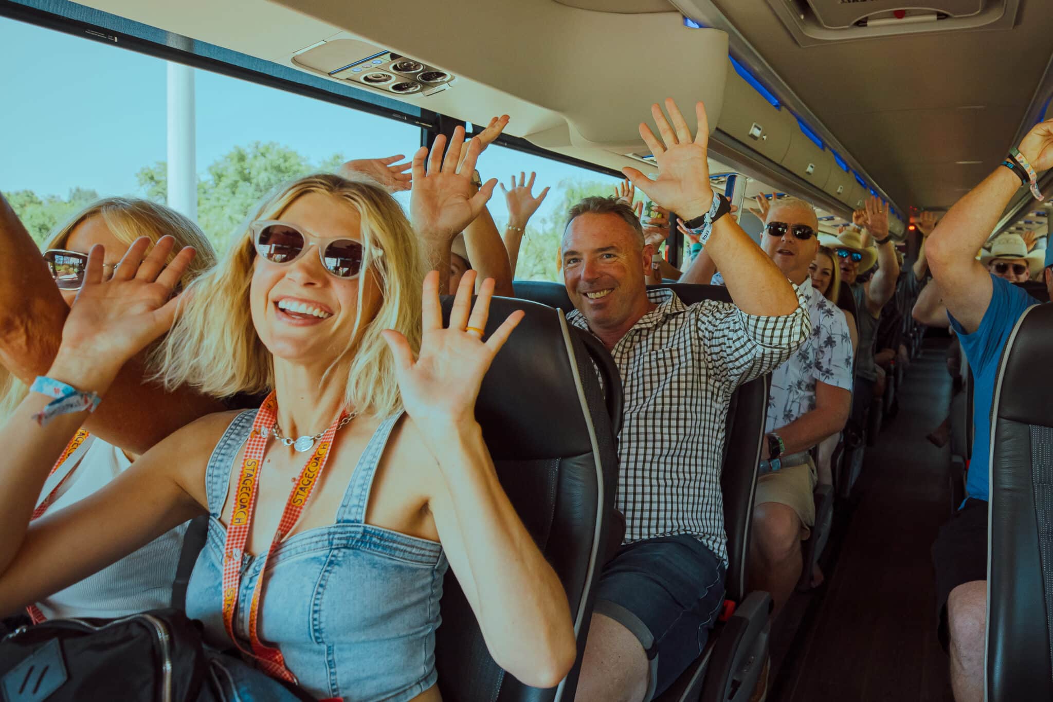 Smiling passengers waving from their seats on a coach bus