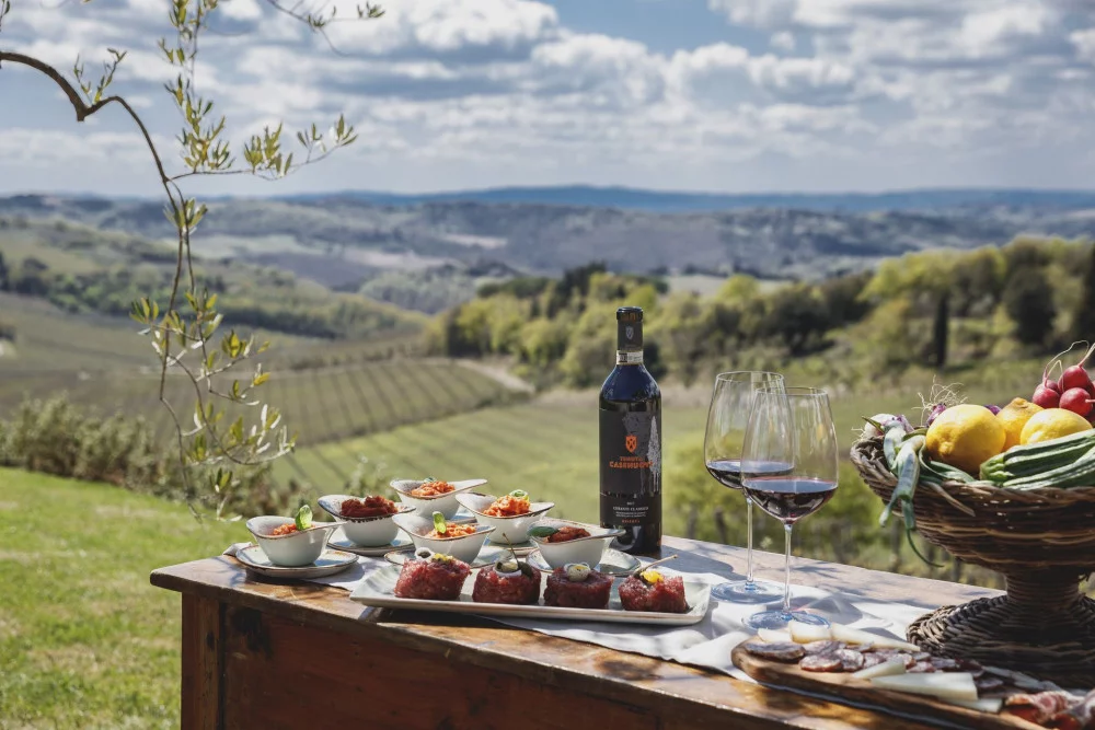 Red wine, two glasses and appetizers on a table overlooking vineyards and hills